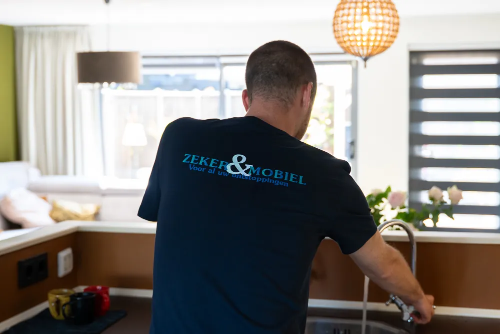 Monteur van Zeker & Mobiel in de keuken bij de afvoer van de vaatwasser