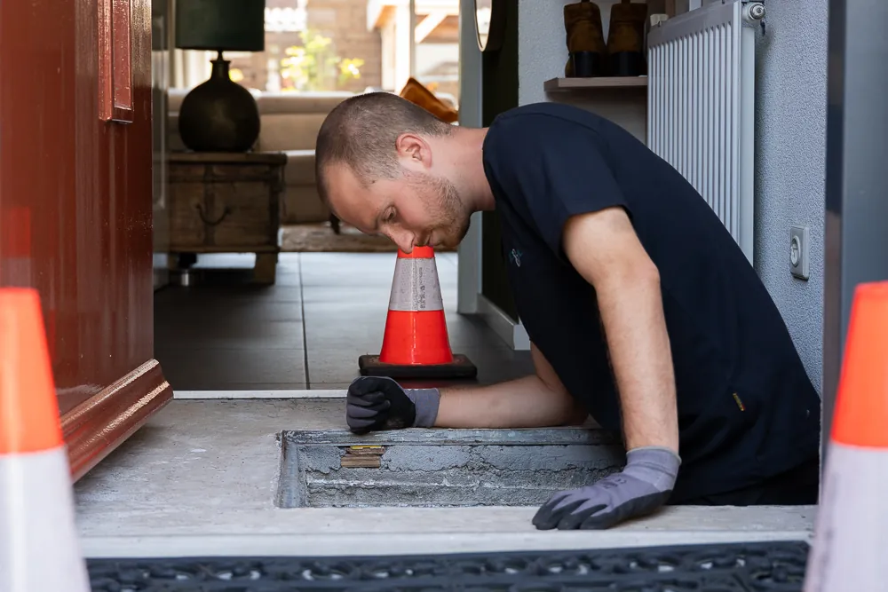 Monteur van Zeker & Mobiel opent de inspectieput om de oorzaak van rioollucht op te sporen